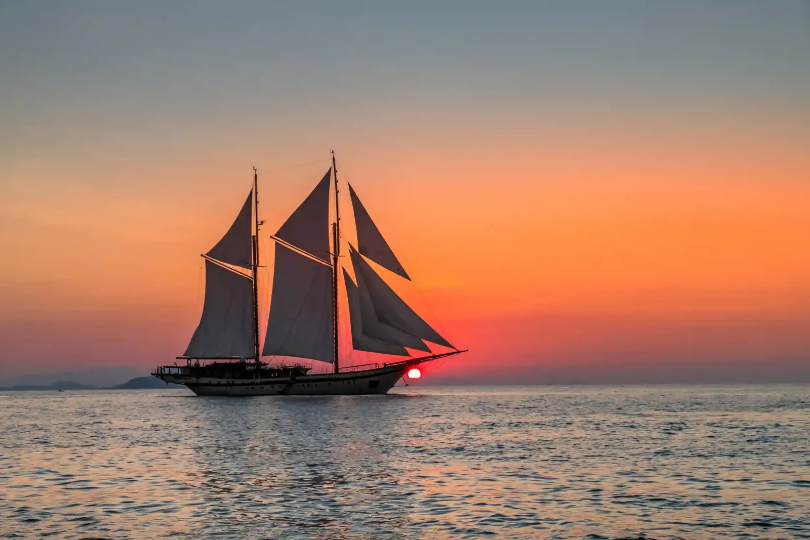 A phinisi at dusk under a red sky
