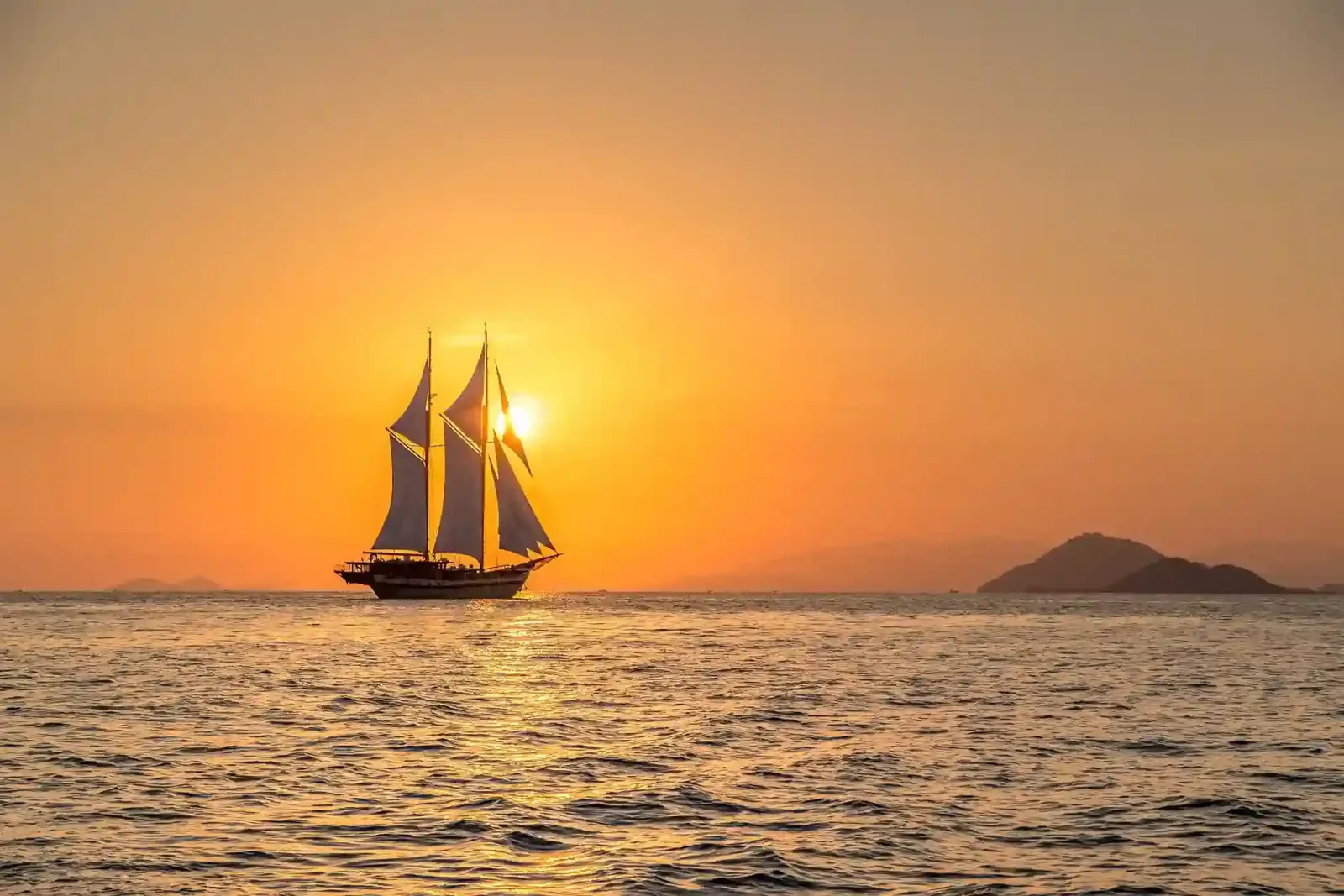 A phinisi silhouetted against the sunset
