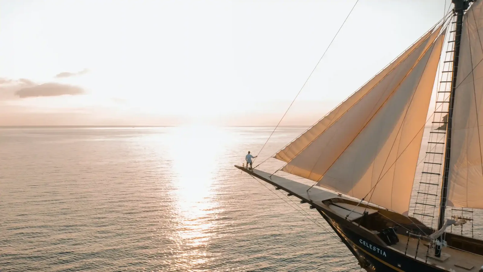 A phinisi under sail at sunset