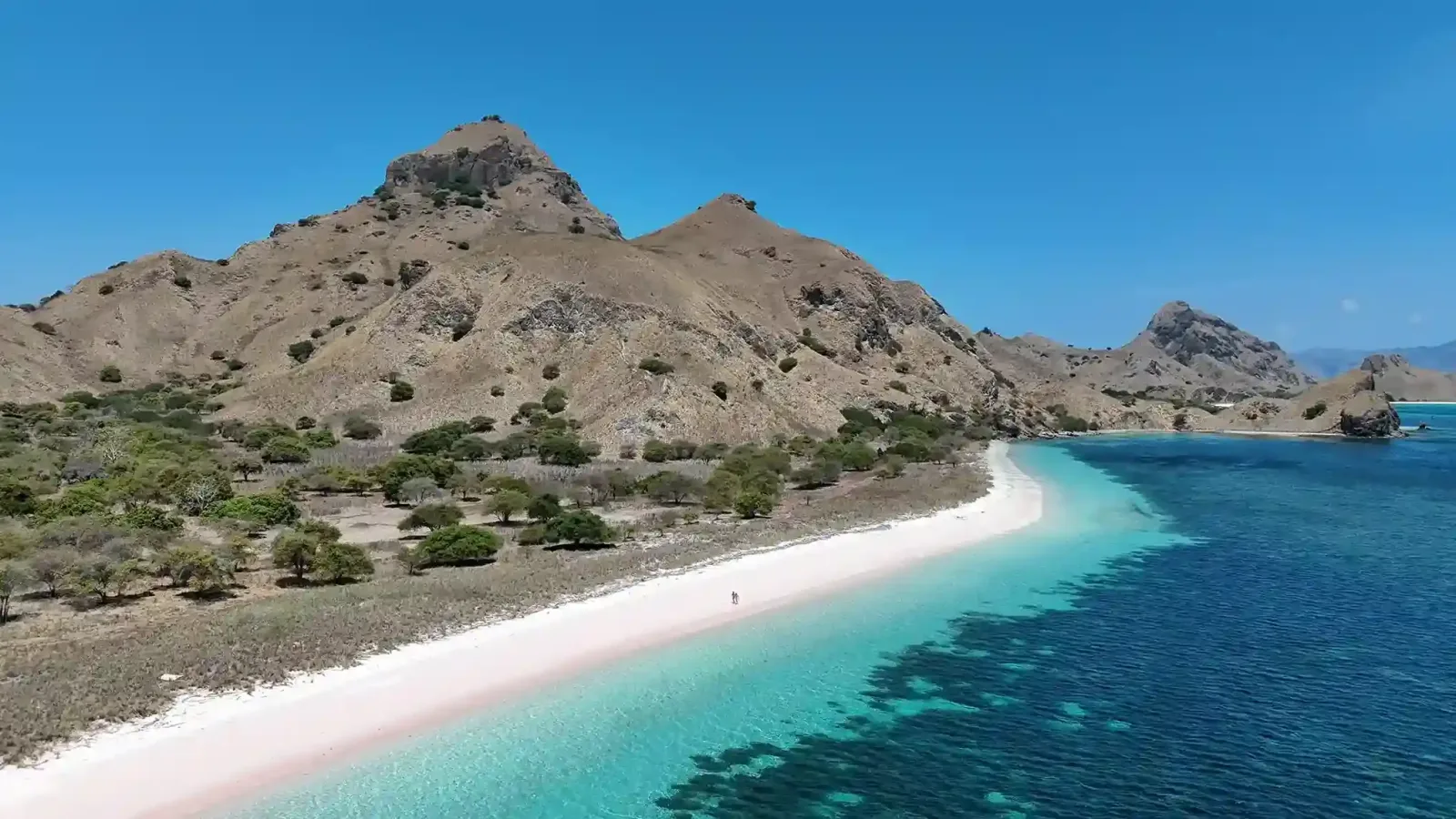 The curve of Pink Beach against turquoise water