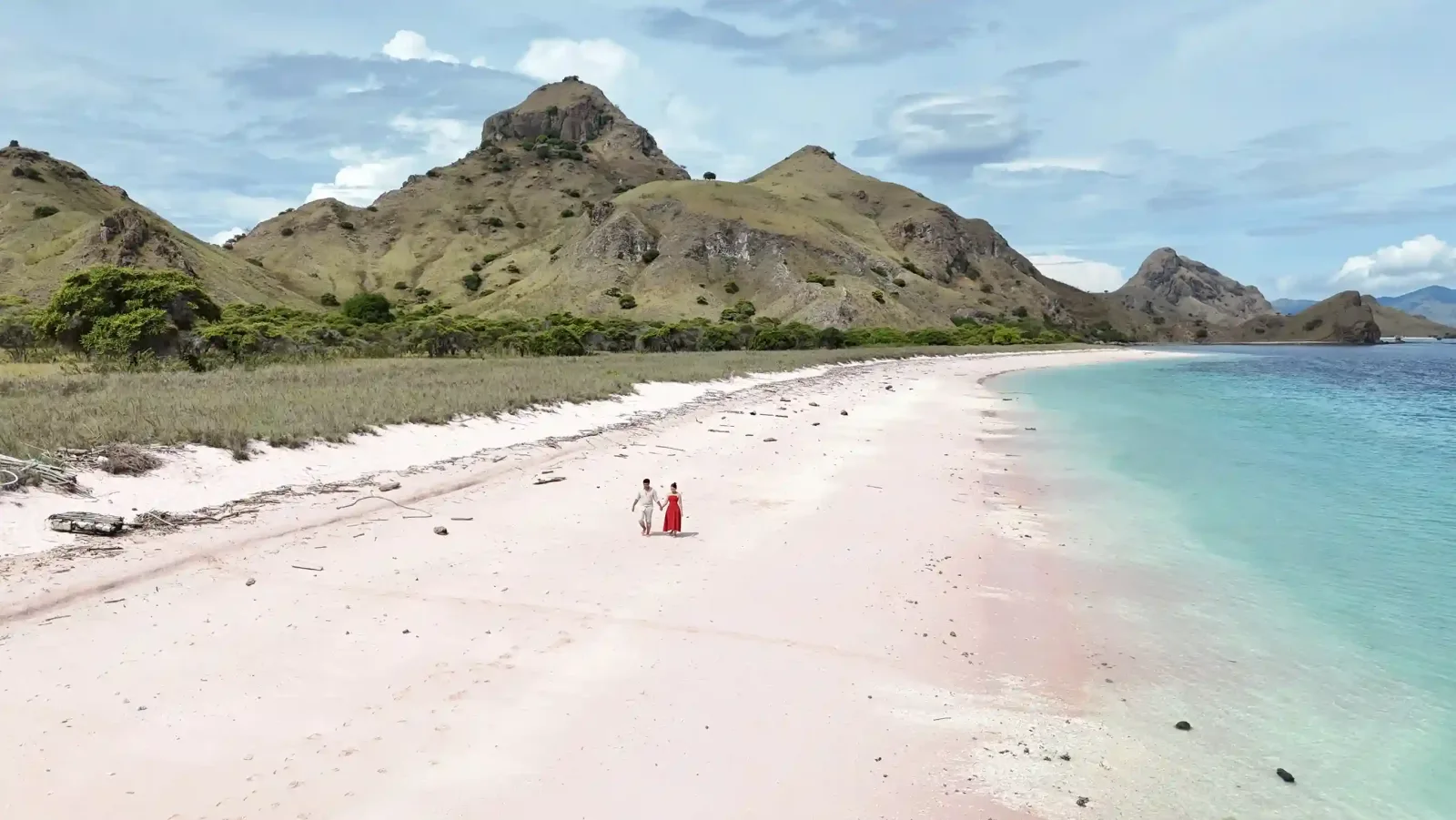 Guests walking the red sand of Pink Beach