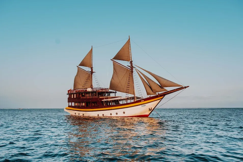 A phinisi sailing below the Komodo hills