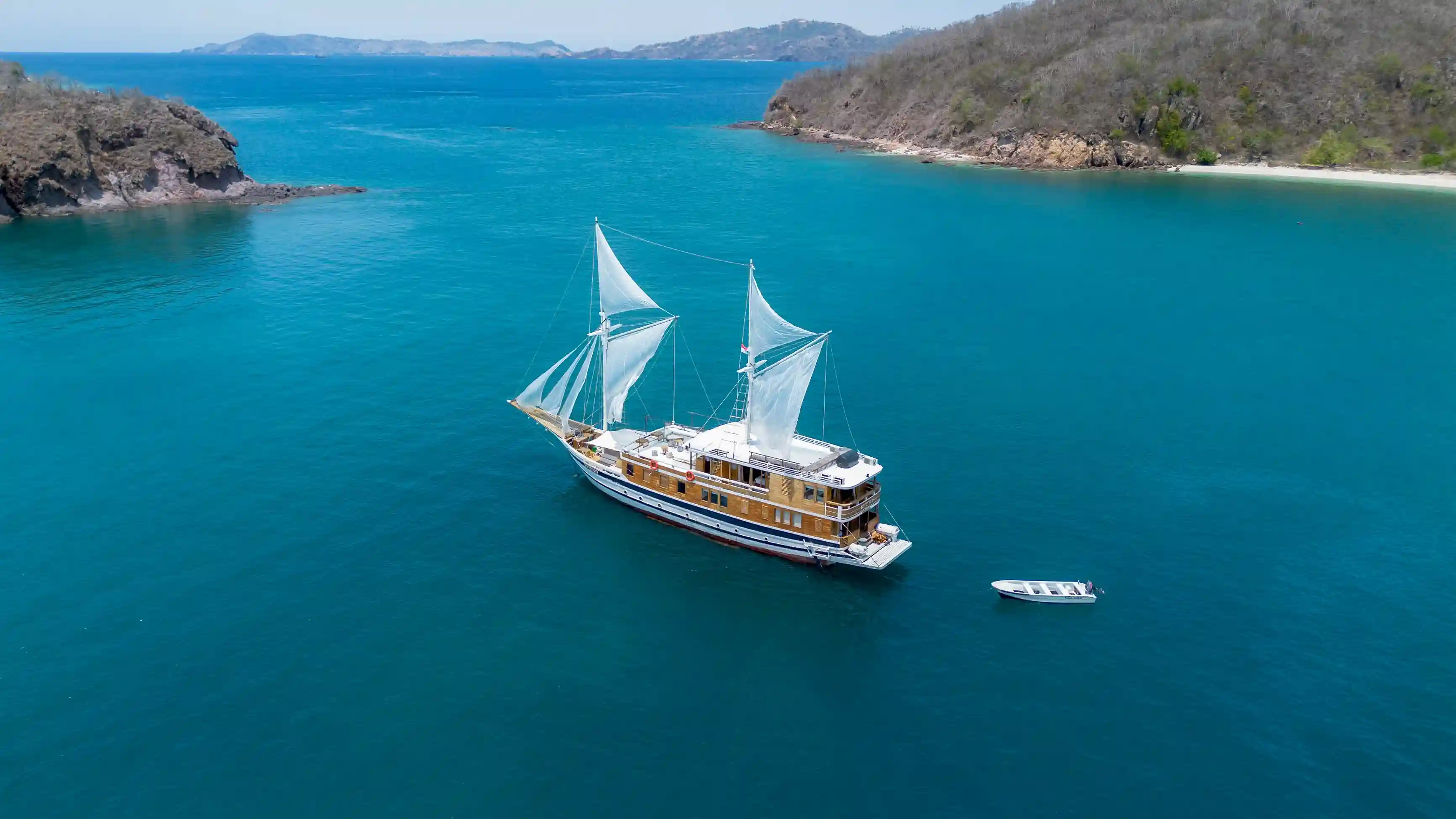Phinisi yacht anchored off a Komodo island at golden hour