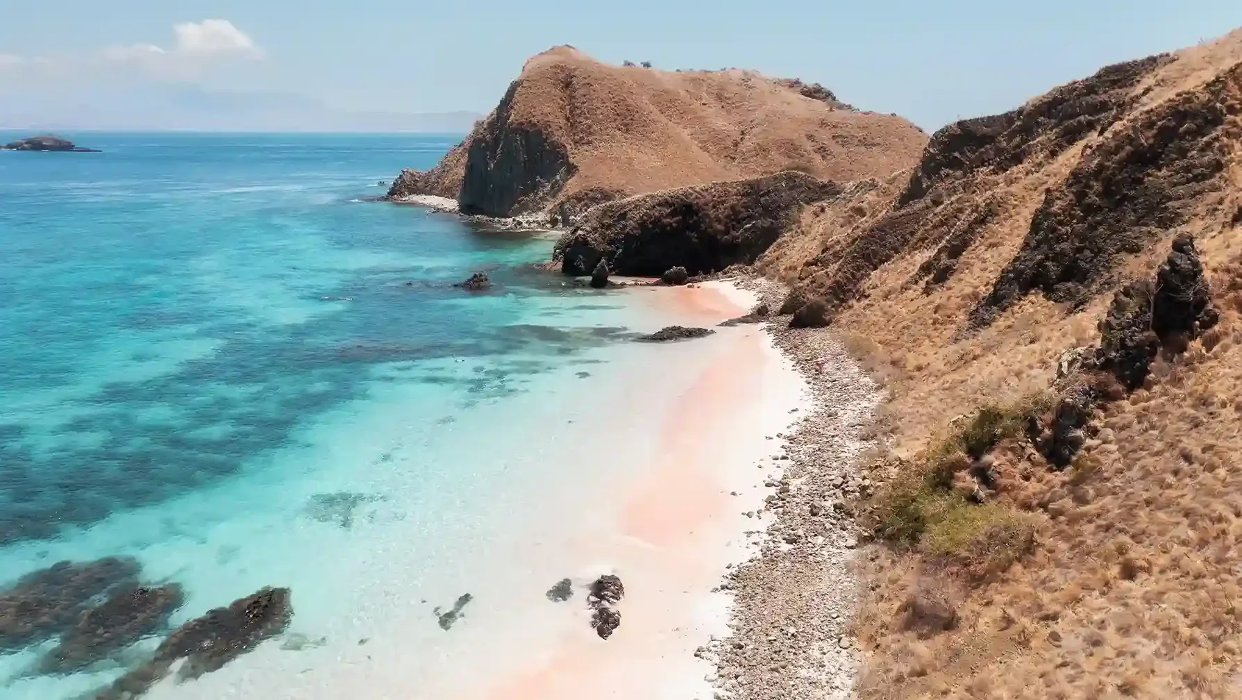 Pink sand meeting clear turquoise water at Pink Beach